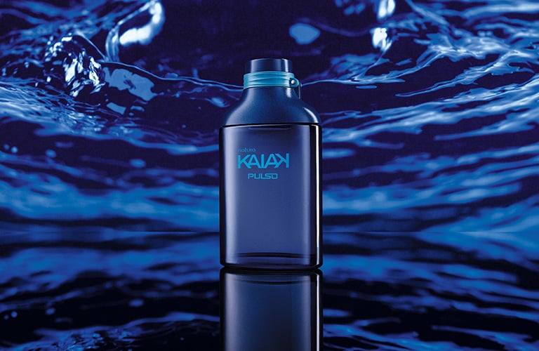 Imagen de un frasco de Kaiak sobre una superficie reflectante, rodeado de agua en tonos azules.